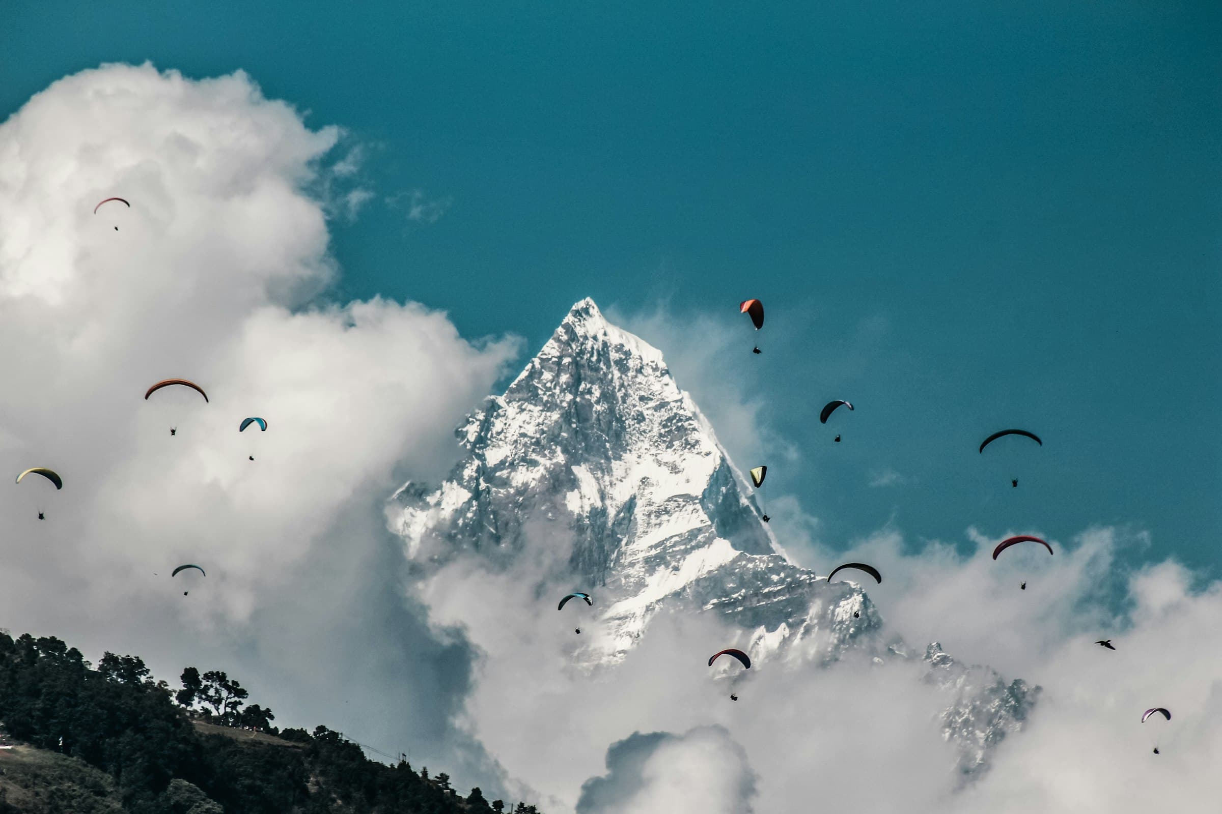 Paragliders circling in front of the snow-covered peak of Machhapuchhre